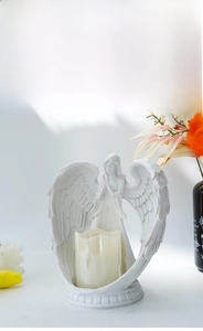 Close-up of white resin angel wings candle holder with intricate feather textures