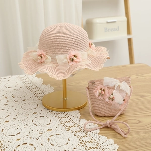 Détail d'un chapeau de paille rose et d'un sac bandoulière assorti avec fleurs en dentelle