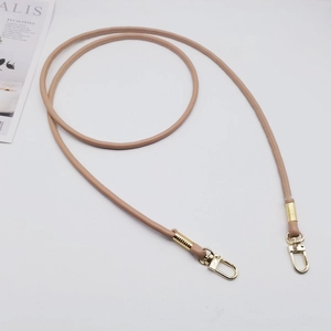 Dettaglio della tracolla tonda in pelle PU beige con moschettoni girevoli in metallo oro