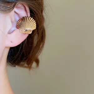 Minimalist gold shell-shaped ear cuff featuring textured metallic radial patterns