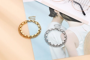 Close-up of gold and silver double-layered chain bracelets with heart charm extension