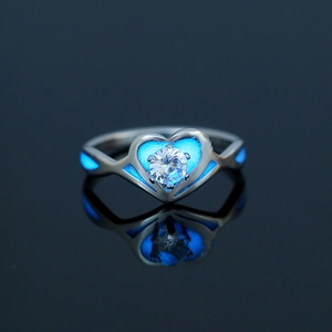 Luminous heart ring in stainless steel with blue glow inlay and crystal on black surface
