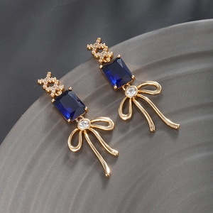 Detailed view of luxury gold earrings with blue gems and intricate crystal cross patterns