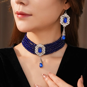 Detail of vintage four-layer blue beaded choker necklace and matching drop earrings on model