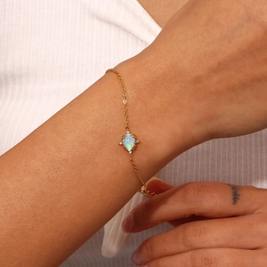 Detail of gold-plated bracelet with teardrop opal pendant and zircon accents on wrist