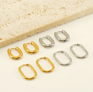 Vue détaillée de boucles d'oreilles créoles ovales dorées et argentées sur pierre