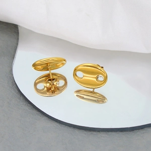 Close-up of polished 18K gold-plated coffee bean earrings on a reflective mirror