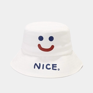 Close-up of white canvas bucket hat featuring a smiley face and NICE embroidery