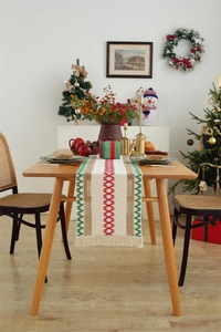 Detail of Christmas table runner with woven cotton linen fringes and red green patterns