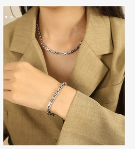 Close-up of silver Cuban link necklace and bracelet set styled with a khaki blazer suit