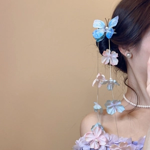 Close-up of blue fabric butterfly hair clip with pastel flower tassels and white pearls