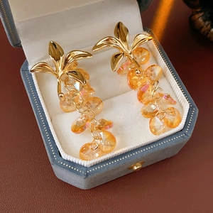 Detailed shot of vintage gold leaf earrings with orange crystal tassels in a velvet box