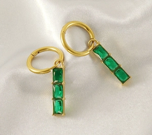 Detailed close-up of emerald-cut green zircons on gold 18K stainless steel drop earrings