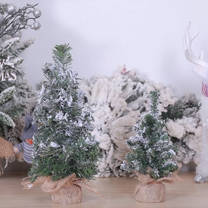 Close-up of two mini flocked Christmas trees with snow-dusted needles and burlap base
