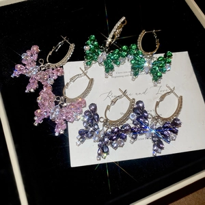 Dettaglio di orecchini a cerchio con farfalla in zircone in rosa verde e blu