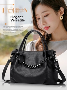 Detail of black pebbled leather tote with metal chain and elegant bow decoration