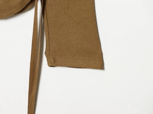Detailed close-up of brown ribbed knit fabric texture with sleeve and tie-up strap