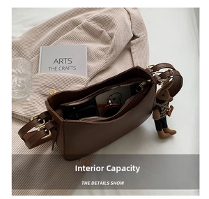 Detail of brown leather shoulder bag with adjustable strap and cute bunny pendant