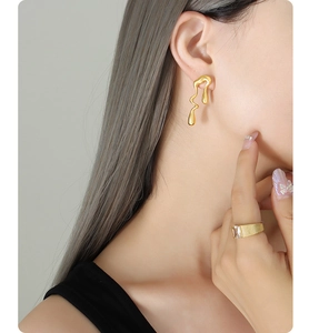 Detalle de pendientes asimétricos bañados en oro de 18K y anillo de circonita en modelo