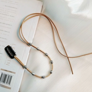 Close-up of suede hair string with metallic silver beads and a snap clip on an open book