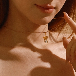Primer plano de un collar con colgante de ángel dorado y circón en una modelo