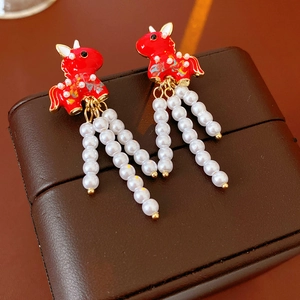 Detailed shot of vintage red enamel unicorn earrings with dangling white pearl tassels