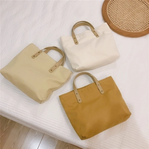Close-up of minimalist canvas tote bags in three colors with metal rivet reinforcements