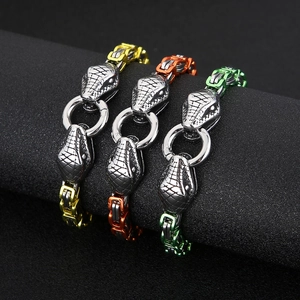 Three snake head steel bracelets in gold, copper, and green on black cylinders