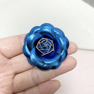 Detailed close-up of a blue PU leather camellia flower brooch with gold accents