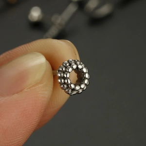 Detailed macro shot of silver stainless steel ball ring piercing with textured beads