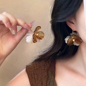 Bohemian acrylic flower drop earrings in amber and cream with metal hooks worn by a model