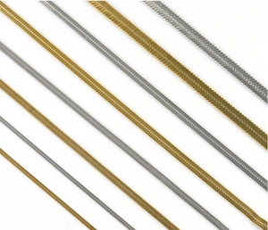 Flat lay of multiple gold and silver herringbone snake chains in various widths and sizes