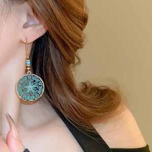 Detail of Bohemian hollow flower drop earrings with turquoise beads on model