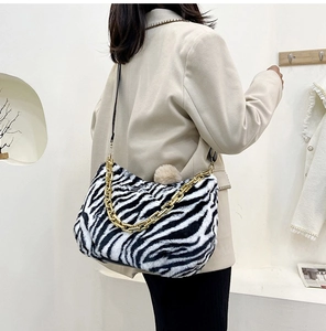Detail of zebra pattern plush tote bag with gold chain strap and fuzzy pompom charm