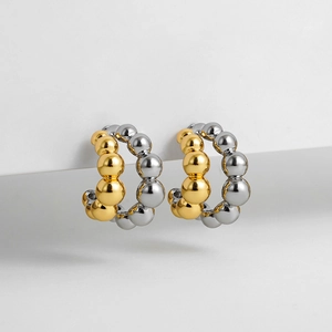 Macro detail of two-tone C-shape beaded earrings with polished gold and silver finish