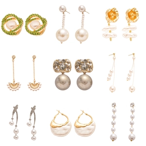 Vintage gold earrings set with pearls, rhinestones and green zircons on white background
