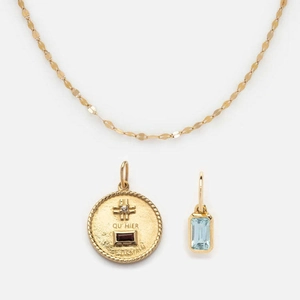 Detailed shot of gold-plated pendant with red gemstone and engraved French text