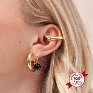 Detail of 925 sterling silver gold earrings set with stacked black smiley face charms