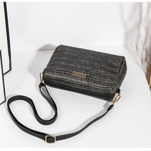 Detail of woven texture crossbody bag with metallic hardware and black shoulder strap