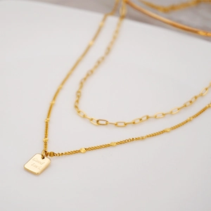Double-layered gold titanium steel necklace with Good Luck pendant and sun flower accents