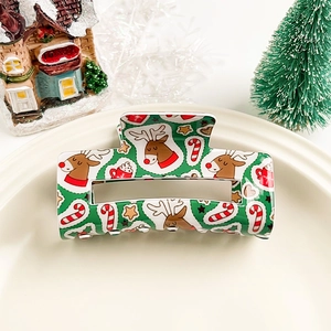 Détail d'une pince à cheveux de Noël verte avec motifs rennes, sucres d'orge et étoiles
