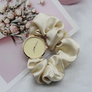Champagne silk scrunchie watch strap with golden case against elegant floral background