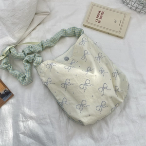 Detailed view of cream lace crossbody bag with purple bows and blue checkered strap
