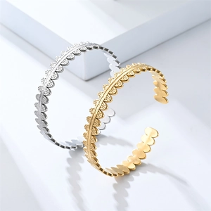 Detailed view of silver and gold open bangles featuring textured shell-like scalloped edges