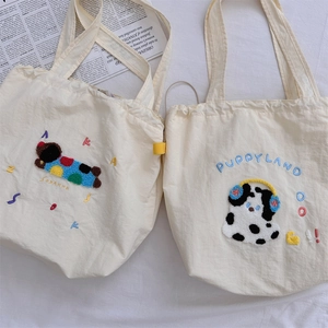 Detail of cream canvas tote bags featuring cute puppy embroidery and plush textures