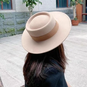 Detail of a beige wool felt wide brim hat with a round crown and dark brown decorative band