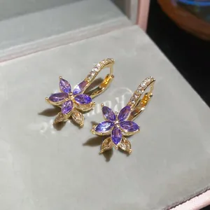 Detail of flower-shaped hoop earrings with purple gems and pavé diamonds on gold base