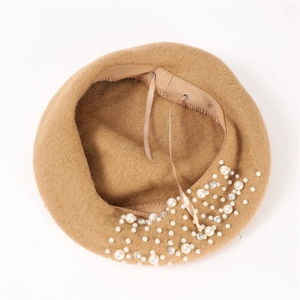Detailed top view of camel wool beret with hand-stitched white pearls and rhinestones