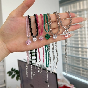 Detail of beaded S925 silver necklaces with crystal hearts and clover charms on wrist