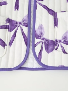 Detail view of white quilted jacket with purple bow patterns and contrast piping